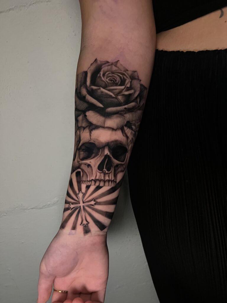 Black and grey realism skull and rose tattoo with high contrast shading