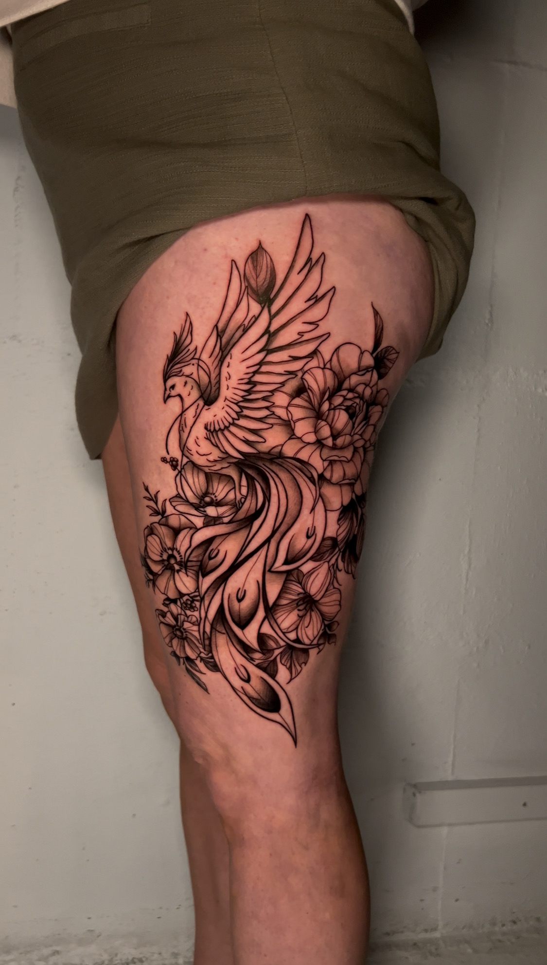 Black and grey realism phoenix tattoo with detailed feathers and dynamic movement